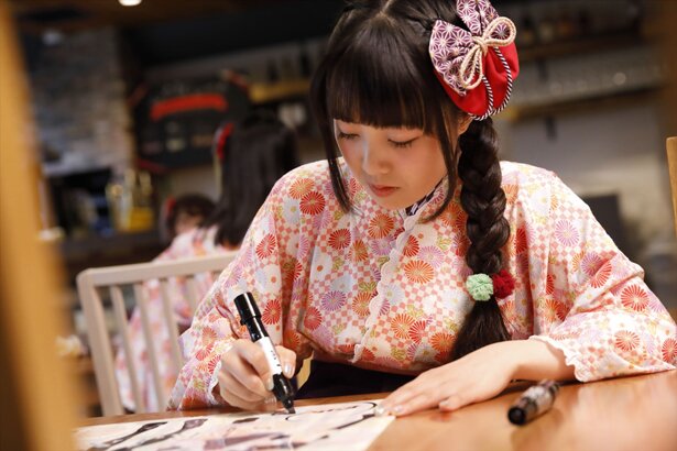 コラボプラン利用者用にポスターにサインをする高橋花林さん<br>(C)温泉むすめ/Enbound, Inc.