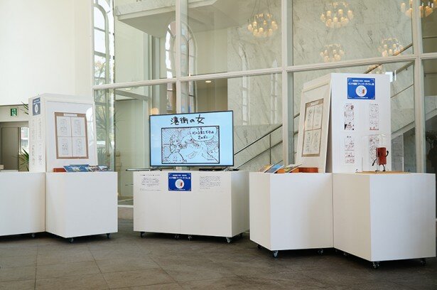 中央のモニターでは4コマコミックをスライドショーで展示。また、貴重な生原画や資料、そしてレンガくんの姿も<br>(C)I.TOON